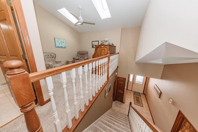 staircase with tile patterned floors, visible vents, high vaulted ceiling, a ceiling fan, and a skylight