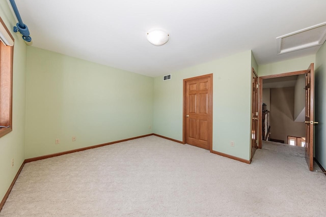 unfurnished bedroom featuring light carpet, visible vents, attic access, and baseboards