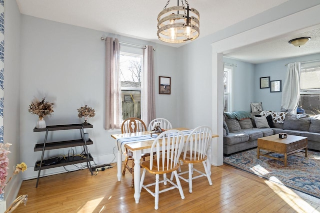 dining area with a notable chandelier, baseboards, and light wood finished floors