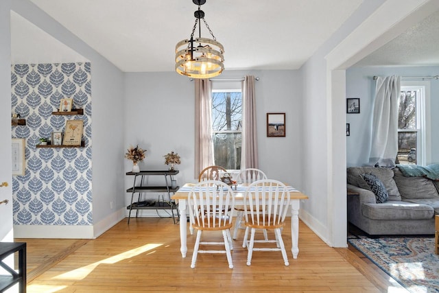 dining area with an inviting chandelier, baseboards, and light wood-style floors