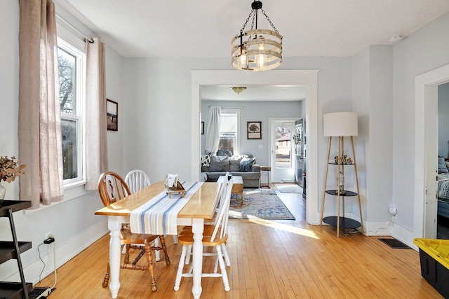 dining area featuring a chandelier, visible vents, light wood-type flooring, and baseboards