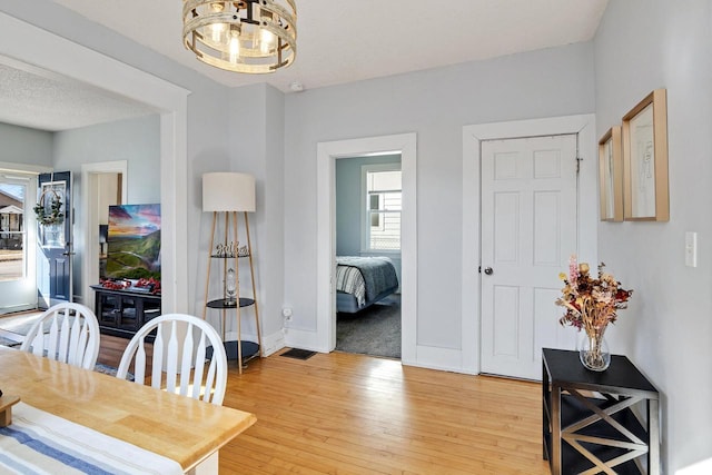 dining room featuring baseboards, light wood-style floors, and a textured ceiling