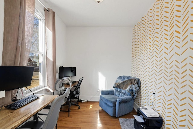 office area featuring an accent wall, wood finished floors, and baseboards