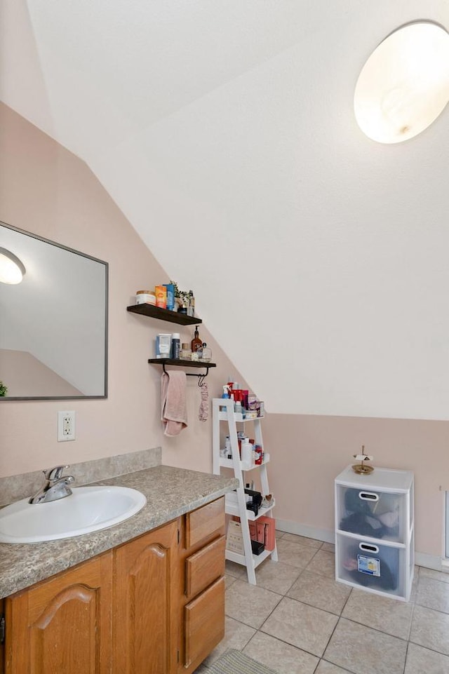 bathroom featuring tile patterned floors, baseboards, lofted ceiling, and vanity