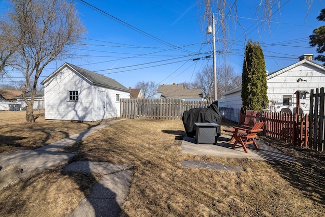 view of yard with an outdoor structure, a fenced backyard, and a patio