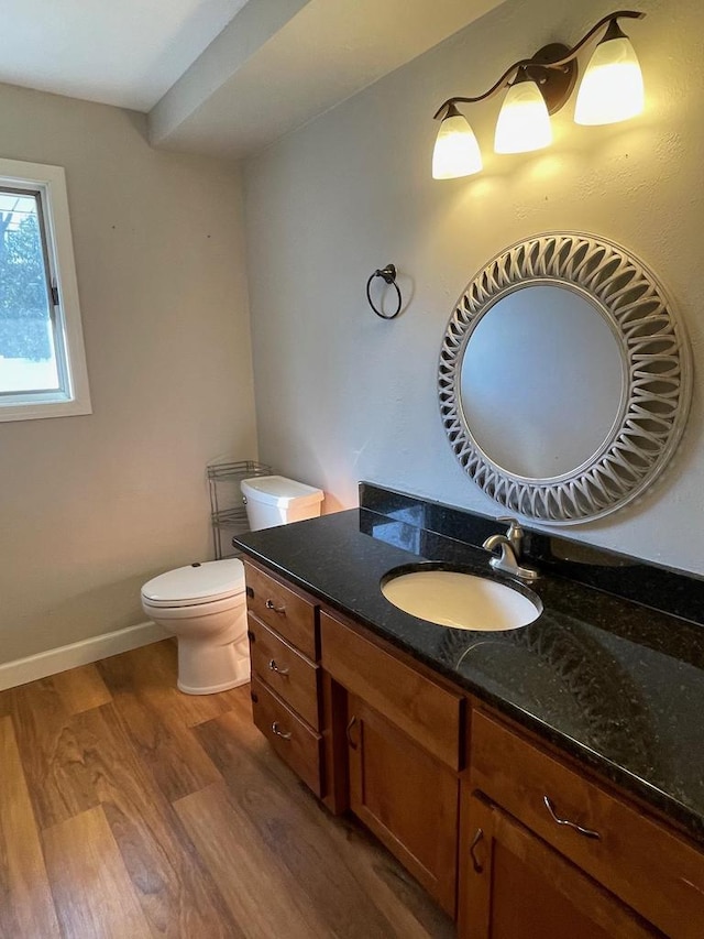 half bath with vanity, toilet, wood finished floors, and baseboards