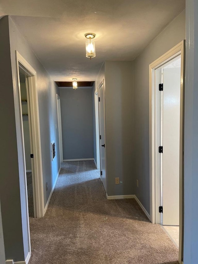 hallway featuring baseboards and carpet