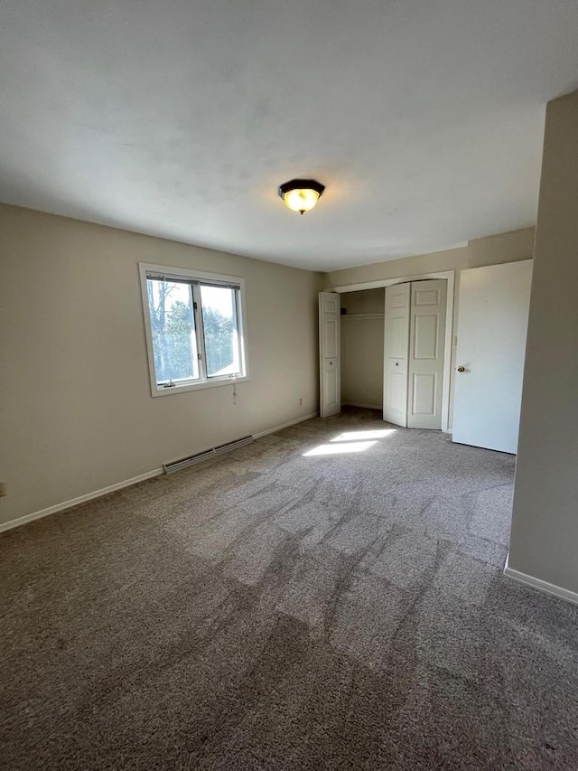 unfurnished bedroom featuring a closet, carpet flooring, baseboards, and a baseboard radiator