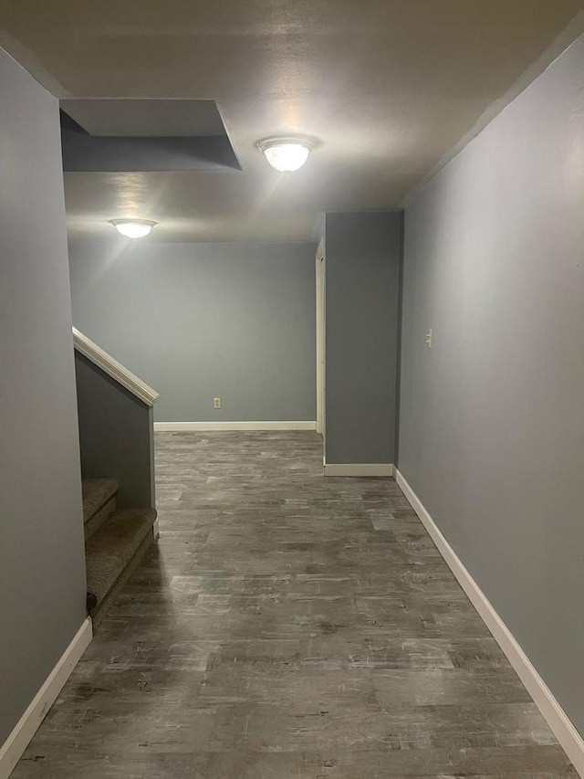 basement featuring stairway, baseboards, and wood finished floors