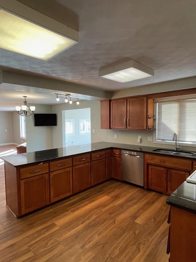 kitchen with a healthy amount of sunlight, dark wood-style flooring, a sink, dishwasher, and brown cabinets