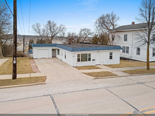 view of front of home featuring concrete driveway, a shingled roof, and a garage