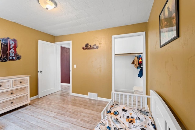 bedroom featuring visible vents, baseboards, light wood-type flooring, and a closet