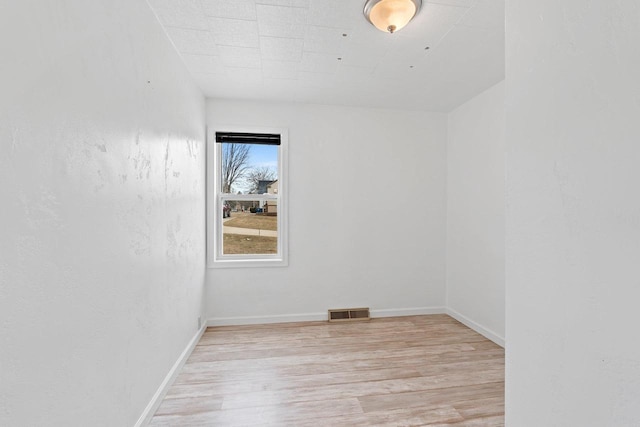 unfurnished room featuring light wood finished floors, visible vents, and baseboards