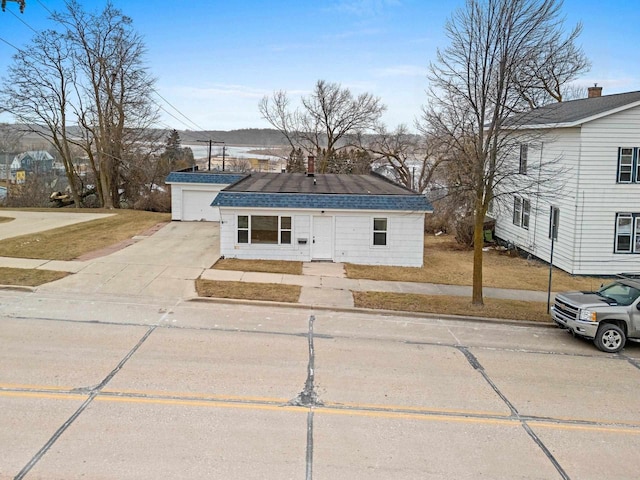 view of front of property featuring a garage, driveway, a front yard, and roof with shingles