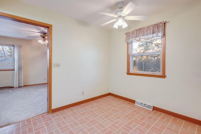 unfurnished room featuring a wealth of natural light, visible vents, baseboards, and brick floor