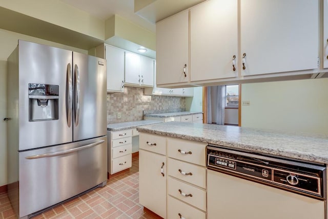 kitchen featuring white cabinetry, white dishwasher, stainless steel fridge with ice dispenser, brick floor, and decorative backsplash