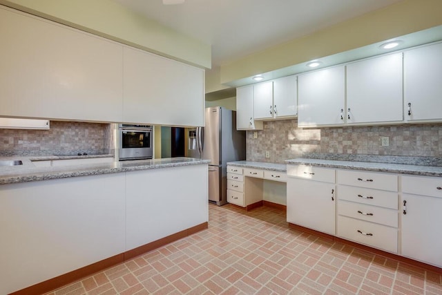 kitchen with decorative backsplash, white cabinets, and appliances with stainless steel finishes