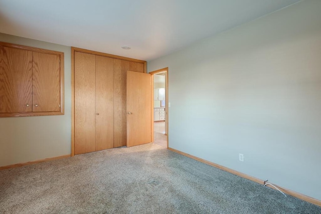 unfurnished bedroom with baseboards, carpet floors, and a closet