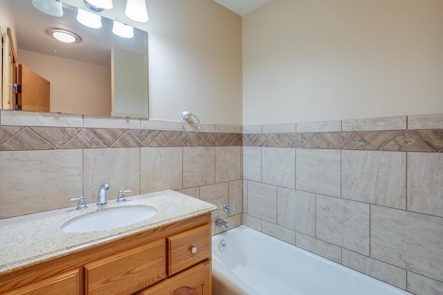 full bath with vanity, tile walls, and a tub