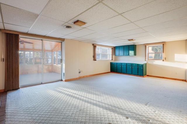 empty room with visible vents, light colored carpet, baseboards, and a drop ceiling