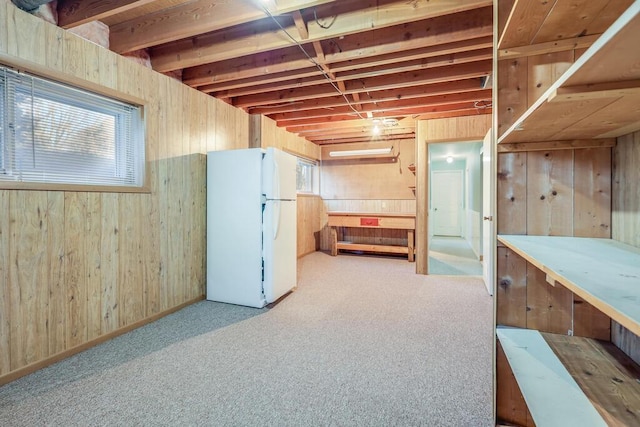 below grade area with wooden walls, a workshop area, freestanding refrigerator, and carpet floors