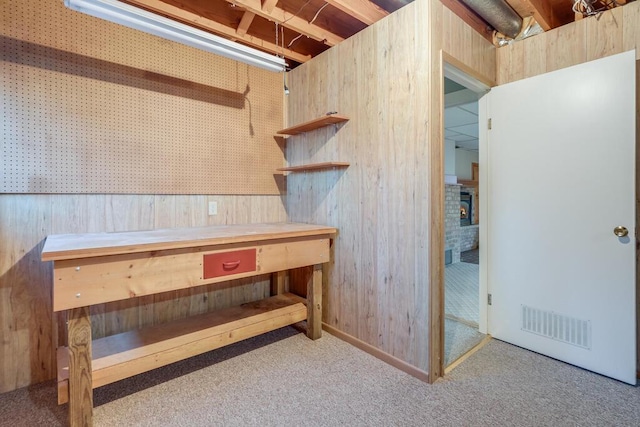 interior space featuring wooden walls, carpet flooring, a fireplace, and visible vents