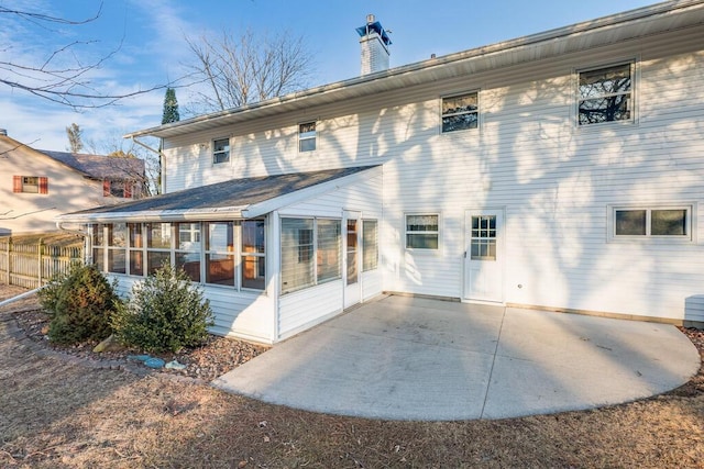 rear view of property featuring a chimney, a patio, and a sunroom