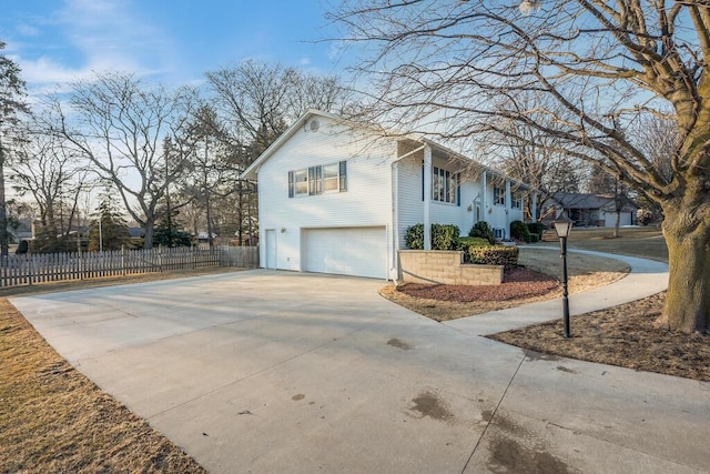 view of side of home featuring a garage, driveway, and fence