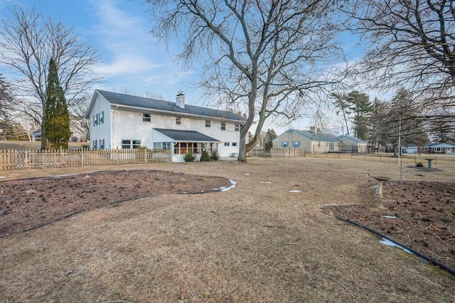 rear view of house featuring fence and a chimney