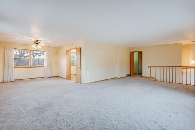 carpeted empty room with ceiling fan with notable chandelier and baseboards