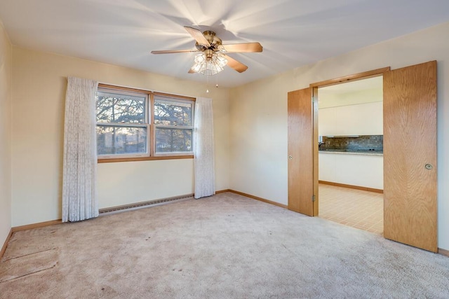 spare room with carpet flooring, ceiling fan, a baseboard heating unit, and baseboards