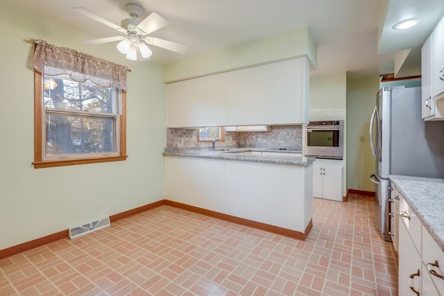 kitchen featuring baseboards, visible vents, stainless steel appliances, white cabinetry, and tasteful backsplash