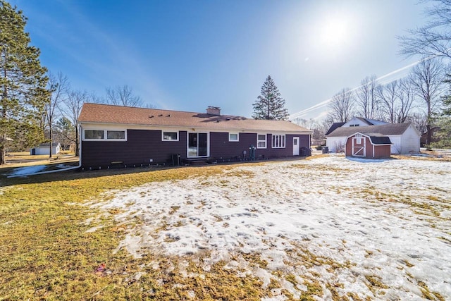 back of property featuring an outbuilding, a storage shed, and a chimney