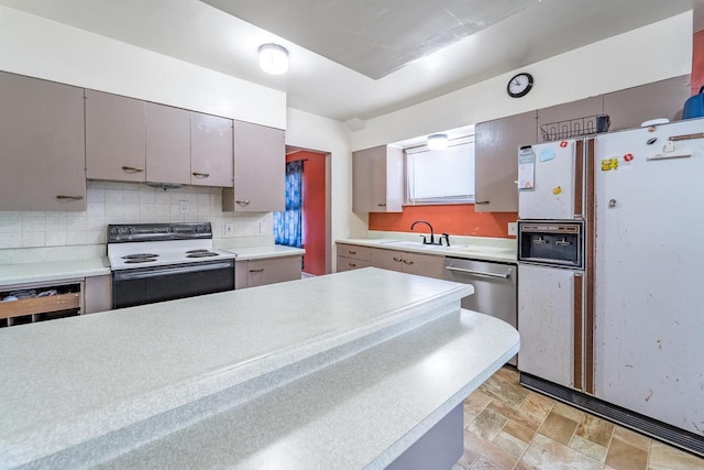 kitchen featuring white appliances, light countertops, tasteful backsplash, and a sink