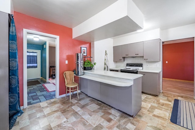 kitchen featuring electric range, gray cabinets, stone finish floor, backsplash, and light countertops