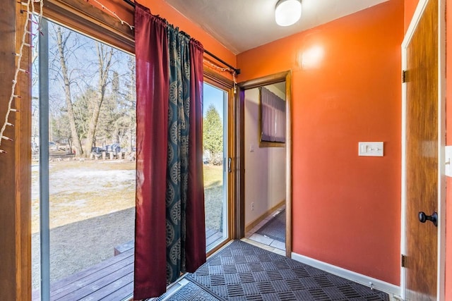 entryway with baseboards and carpet