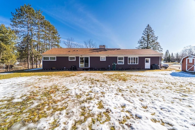 rear view of property featuring an outbuilding, a storage shed, and a chimney