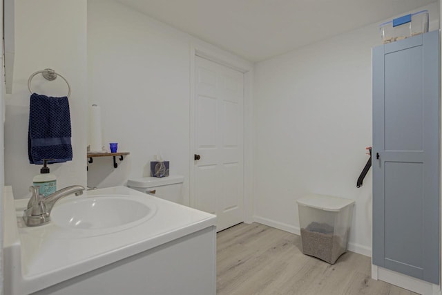 bathroom with vanity, toilet, wood finished floors, and baseboards