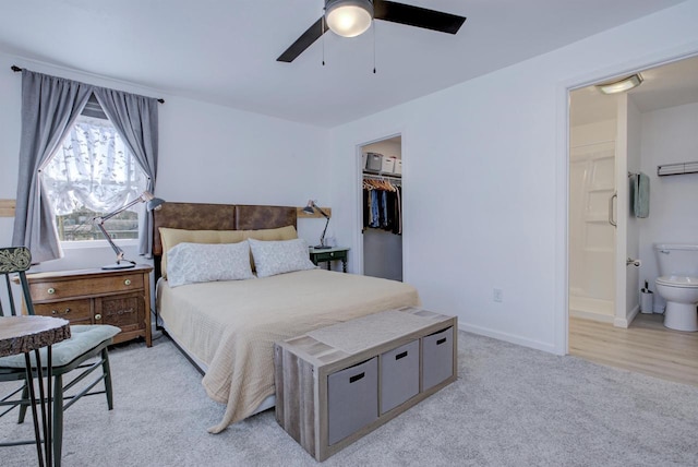 bedroom with baseboards, a closet, a walk in closet, light colored carpet, and connected bathroom