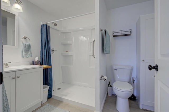 full bathroom featuring vanity, toilet, wood finished floors, and a shower stall