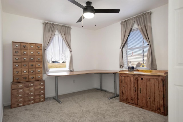 office space featuring light colored carpet, baseboards, and a ceiling fan