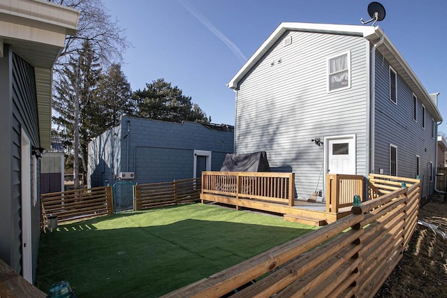 rear view of property with a deck, a yard, and fence