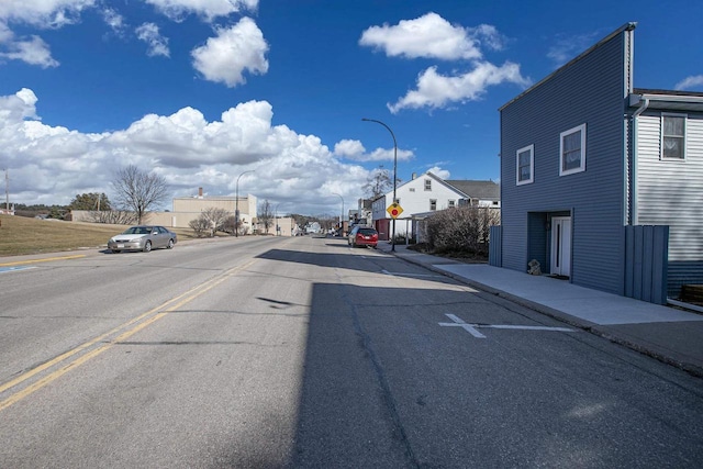 view of road featuring curbs, traffic signs, street lights, and sidewalks