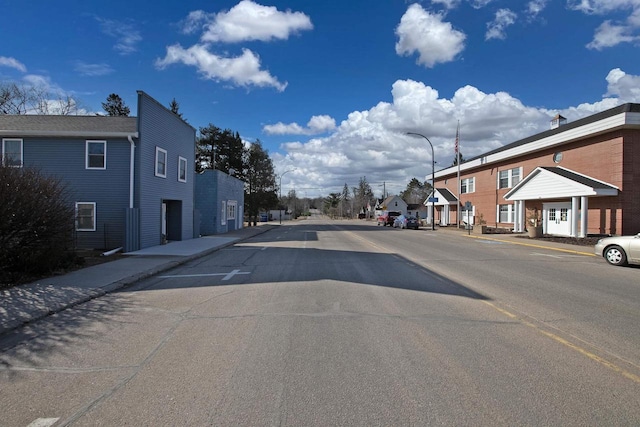 view of street with street lights, curbs, sidewalks, and a residential view