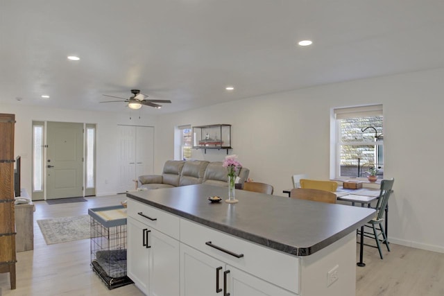 kitchen with recessed lighting, light wood-style floors, dark countertops, and white cabinetry