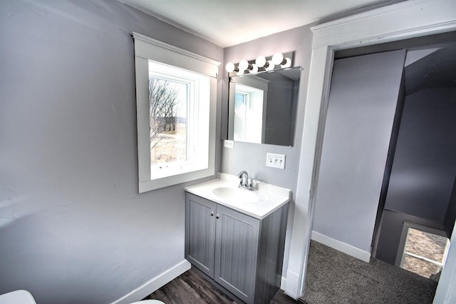 half bathroom with toilet, vanity, and baseboards