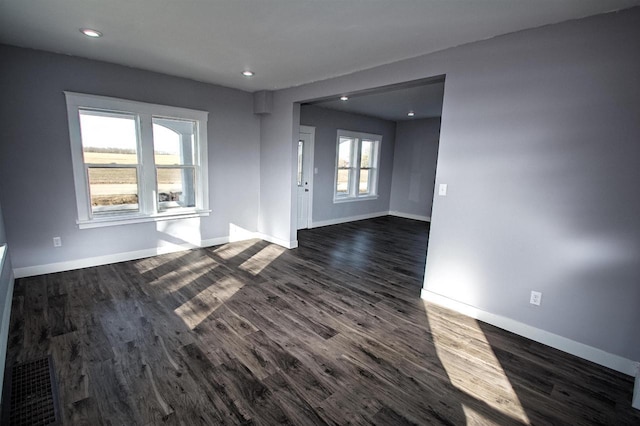 spare room with visible vents, baseboards, and dark wood-style floors