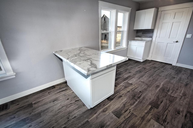 kitchen featuring baseboards, a peninsula, dark wood finished floors, and white cabinetry