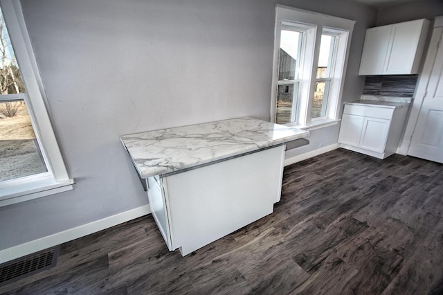 kitchen with white cabinetry, dark wood-type flooring, baseboards, and visible vents