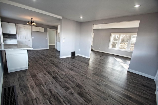 unfurnished living room featuring dark wood-type flooring, recessed lighting, baseboards, and visible vents